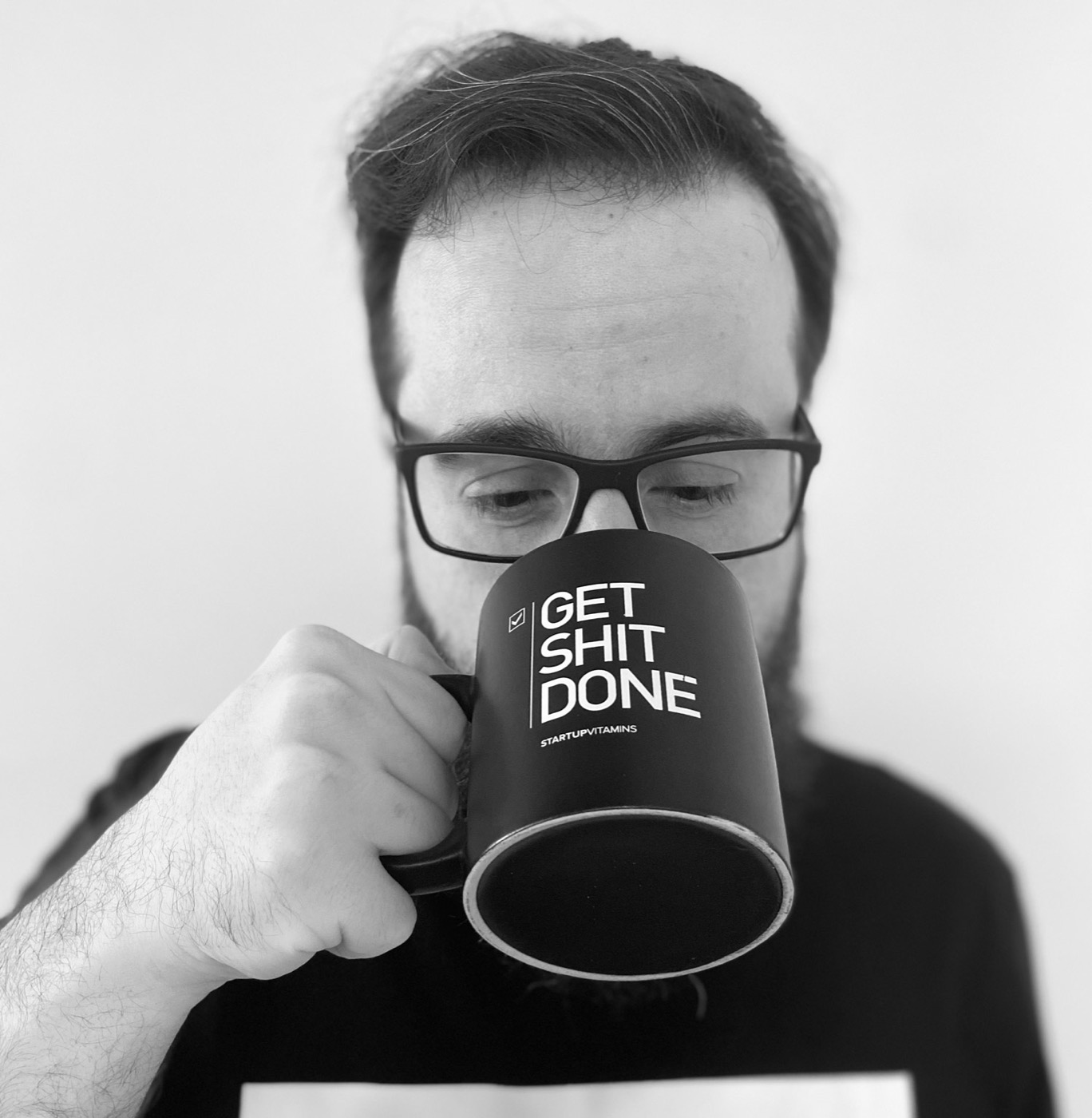 Michel Scoz tomando café numa caneca escrita Get shit done.